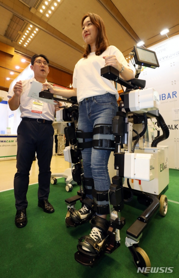 8일 오후 서울 강남구 코엑스에서 열린 2018 국제 병원 및 의료기기 산업박람회를 찾은 관람객이 외골격 제어형 보행재활로봇을 체험하고 있다.