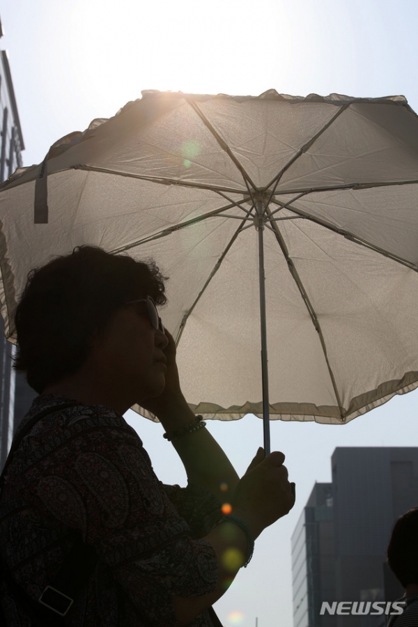 서울에 폭염주의보가 발령된 24일 오후 서울 종로구 광화문 사거리에서 한 시민이 양산을 쓰고 걸어가고 있다.