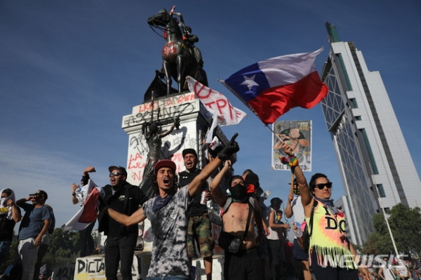 30일(현지시간) 칠레 수도 산티아고에서 반정부시위대가 구호를 외치며 시위하고 있다. 세바스티안 피녜라 칠레 대통령은 이날 시위로 인한 내부 혼란으로 11월 APEC과 12월 기후변화협약 당사국 총회(COP) 개최를 취소한다고 밝혔다.