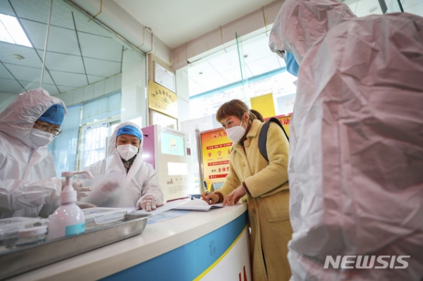 중국 후베이성 우한의 한 지역 보건소에서 지난 27일 의료진이 신종코로나바이러스 감염증 감염으로 의심되는 한 여성과 대화하고 있다.