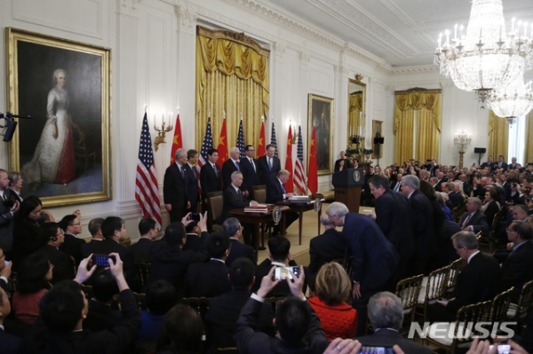 15일(현지시간) 미국 워싱턴 백악관에서 류허 중국 부총리(왼쪽)과 도널드 트럼프 미국 대통령(오른쪽)이 앉아 1단계 미중 무역합의문에 서명하고 있다.