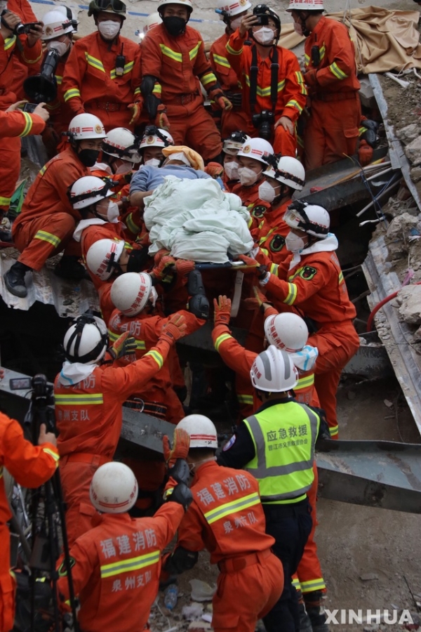 지난 7일(현지시간) 중국 푸젠성 취안저우시에서 붕괴한 신자 호텔 사고 현장에서 10일 구조대가 한 남성을 매몰 69시간 만에 구조해 구급차로 옮기고 있다.