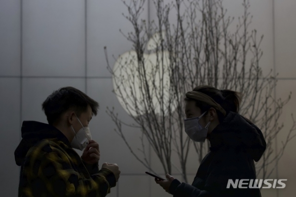 2월26일(현지시간) 중국 베이징에서 마스크를 쓴 쇼핑객들이 애플 로고 앞을 지나고 있다. 애플은 신종 코로나바이러스 감염증(코로나19) 확산을 우려해 중화권을 제외한 전 지역의 매장을 닫기로 했다고 14일 밝혔다.