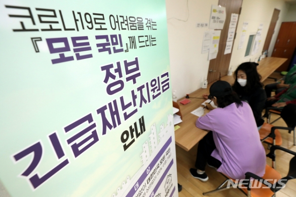 정부 긴급재난지원금 현장접수 첫날인 18일 서울 송파구 삼전동 주민센터에서 시민들이 지원금 접수를 위해 신청서를 작성하고 있다.