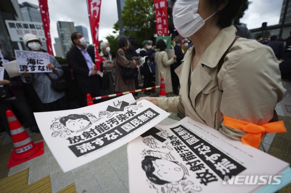 13일 일본 도쿄의 총리관저 밖에서 후쿠시마 원전 오염수 해양 방류에 반대하는 시민들이 "방사능 오염수를 바다에 버리지 말라"라고 쓰인 전단을 나눠주고 있다.  일본 정부는 지역 어민과 주민들의 반대 속에 후쿠시마 원전에서 나온 대량의 방사능 오염수를 2년 후에 태평양으로 방류하기로 했다. 2021.04.13.