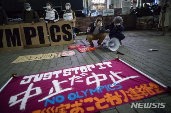25일 일본 도쿄에서 2020 도쿄올림픽·패럴림픽 강행에 반대하는 시위대가 "올림픽 중단"이라는 현수막을 거리에 깔고 스피커를 통해 구호를 외치고 있다. 2021.03.26.